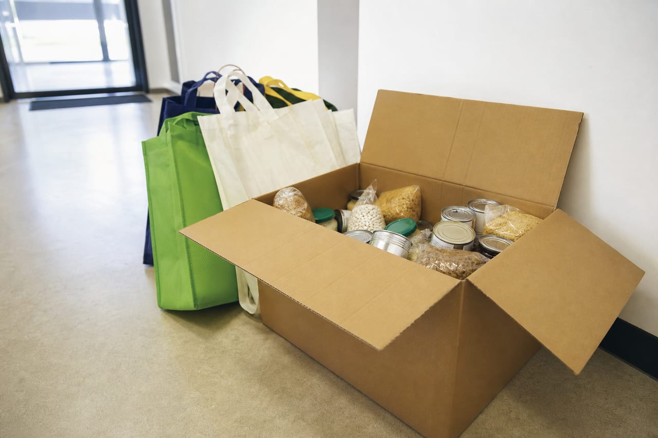 Grocery box ready for delivery beside reusable bags